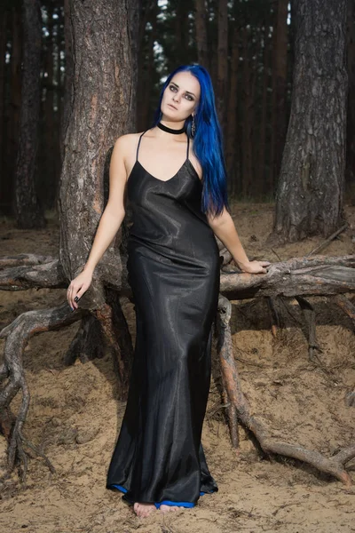 Beautiful woman with dark blue hair dressed in black dress in th — Stock Photo, Image