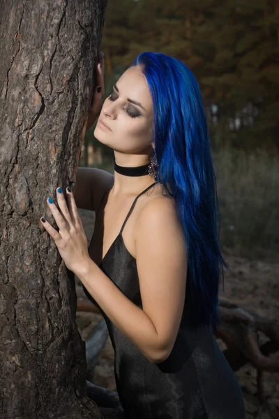 Piękna kobieta z ciemno niebieskie włosy, ubrany w czarny strój w th — Zdjęcie stockowe