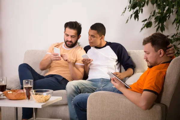 Amigos usando telefones celulares ou inteligentes em casa — Fotografia de Stock