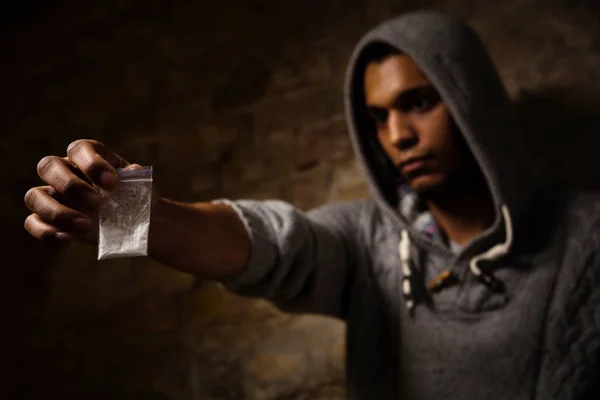 Drogensüchtiger zeigt Betäubungsmittel und hält sie vor sich. Drogenabhängige variiert, ob sie Drogen in Form von weißem Pulver einnehmen sollen. — Stockbild Drogen- und Betäubungsmittelkonzept — Stockfoto