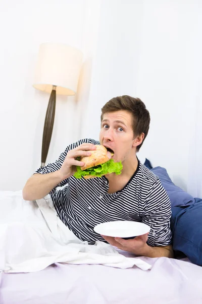 Hombre soltero comiendo en la cama — Foto de Stock