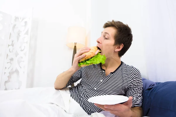 Pria lajang makan di tempat tidur — Stok Foto
