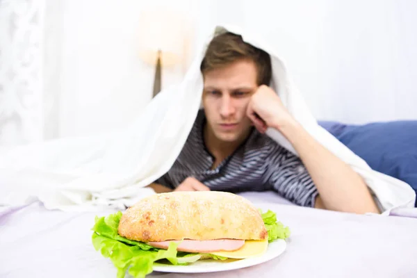 Hombre soltero comiendo en la cama — Foto de Stock