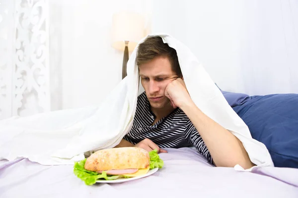 Hombre soltero comiendo en la cama — Foto de Stock