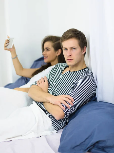 Pareja usando el teléfono móvil en la cama —  Fotos de Stock
