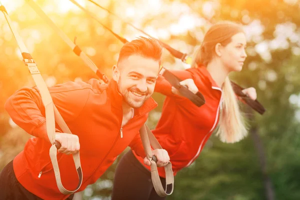 Спортивные тренировки мужчин и женщин в парке с TRX — стоковое фото