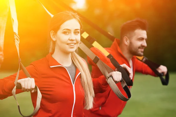 Спортивные тренировки мужчин и женщин в парке с TRX — стоковое фото