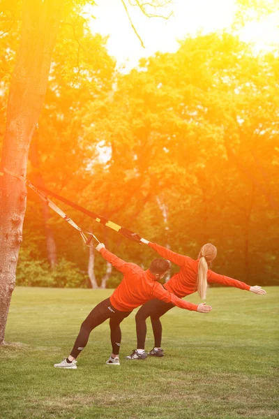 Entrenamiento deportivo de hombre y mujer en el parque con TRX — Foto de Stock