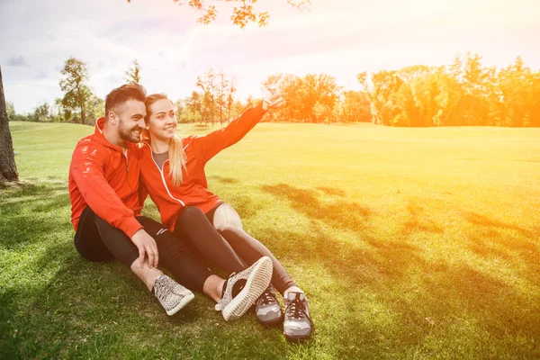 Urheilu mies ja nainen tekee selfietä puistossa — kuvapankkivalokuva
