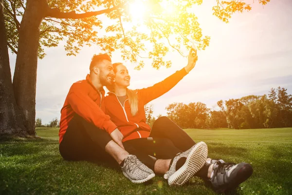 Sport man och kvinna att göra selfies i park — Stockfoto