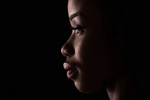Retrato de vista lateral de modelo de pele escura em um fundo preto . — Fotografia de Stock