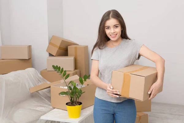 Jonge vrouwelijke staande met in de kamer vol met vakken. — Stockfoto