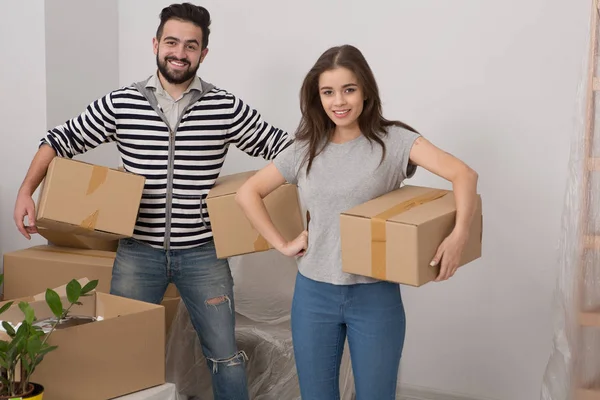 Счастливые муж и жена несут коробки в своем новом доме . — стоковое фото