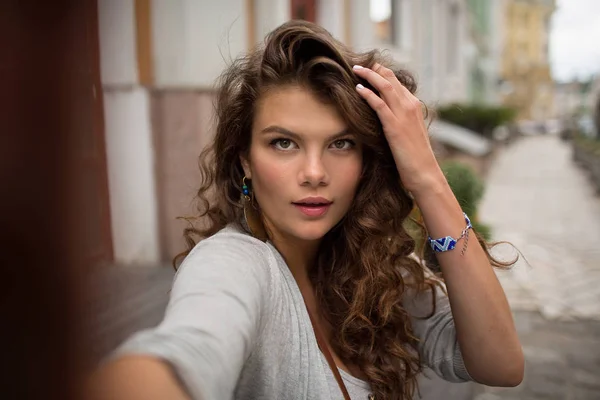 Toeristische vrouw maken selfie geschoten, het aanraken van haar lange bruine haren. — Stockfoto