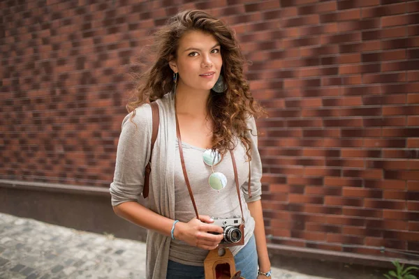 カメラのためにポーズと笑顔の通りに立っている若い観光客女性. — ストック写真