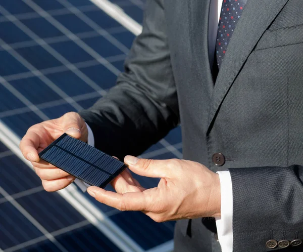 Empresário segurando elemento fotovoltaico em suas mãos . — Fotografia de Stock