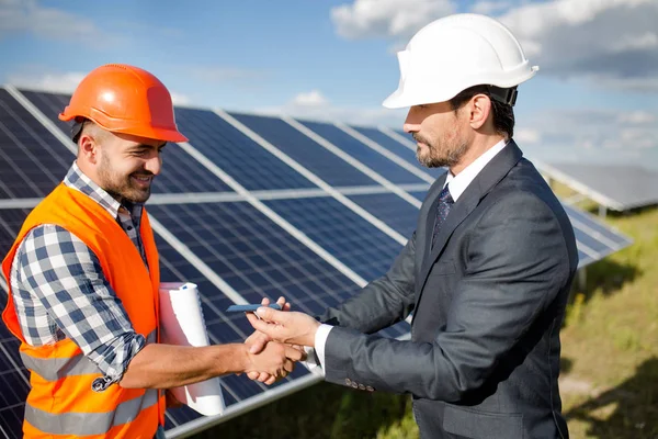 Businessman holding photovoltaic detail and shaking hand to a foreman. — Stock Photo, Image