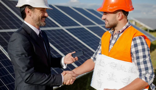 At solar energy station business client and foreman shaking hands.