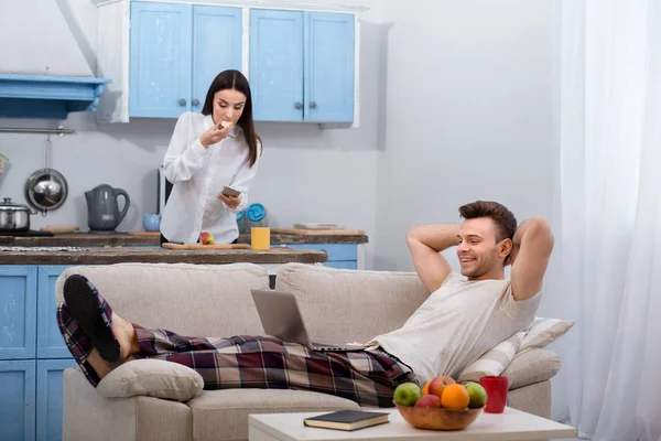 Man liggande på soffan medan hans hustru förbereder sig för att gå till jobbet. — Stockfoto