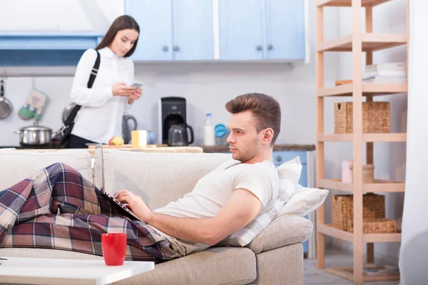 Junge Frau googelt zur Arbeit, während ihr Mann zu Hause bleibt und arbeitet. — Stockfoto