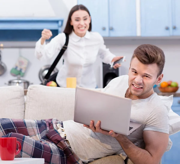 Marito pigro sul divano e sua moglie furiosa, che va al lavoro . — Foto Stock