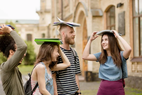 Vista de cerca de estudiantes multiétnicos sosteniendo libros en sus cabezas . — Foto de Stock