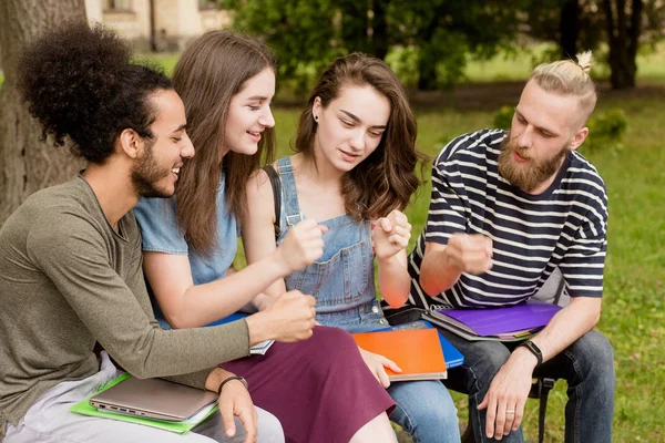 Studenti multietnici seduti sulla panchina a giocare . — Foto Stock