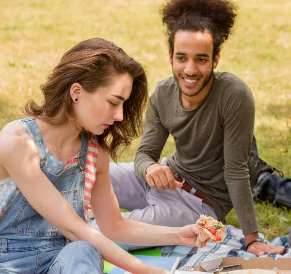 Sudents chico y chica teniendo picnic comiendo pizza . — Foto de Stock