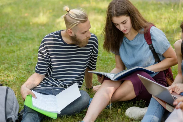 Studenti ragazzo e ragazza seduto su erba studiare . — Foto Stock