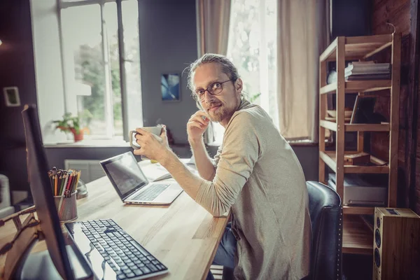 Vista lateral do jovem freelancer sentado no escritório em casa trabalhando . — Fotografia de Stock