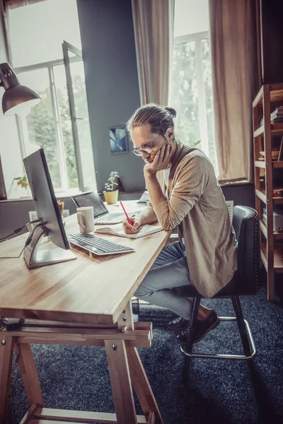 Vista laterale sull'uomo che lavora come freelance al tavolo di legno . — Foto Stock