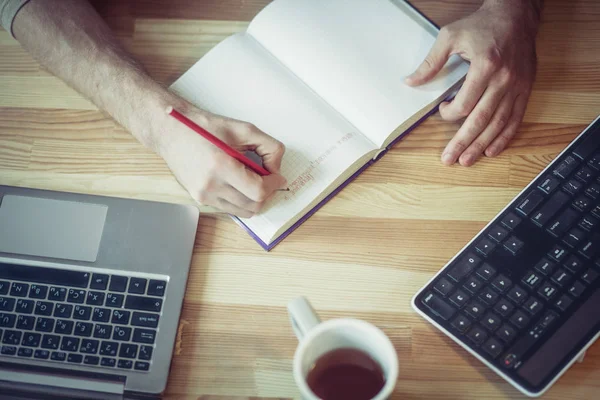 Visão superior do homem freelancer escrevendo em notebook na mesa de madeira . — Fotografia de Stock