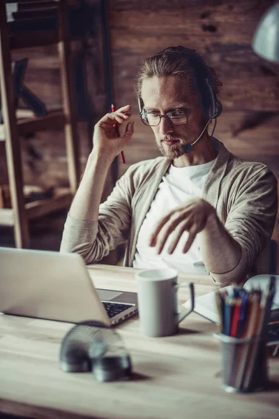 Freelancer usando auriculares manos libres para trabajar en línea . — Foto de Stock