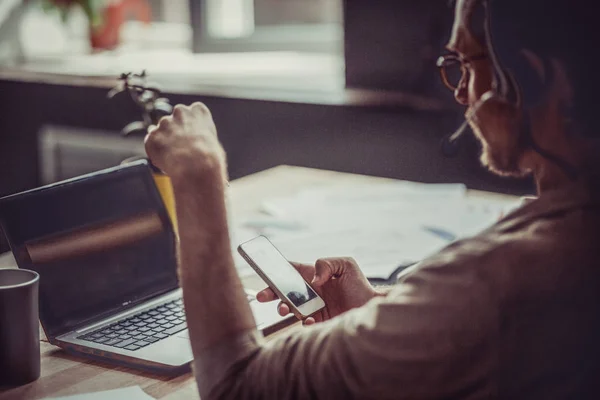 Achteraanzicht van freelance man met mobiele telefoon in zijn hand. — Stockfoto