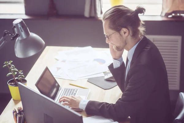 Hombre trabajando en freelance, hablando por teléfono y escribiendo en el portátil . — Foto de Stock