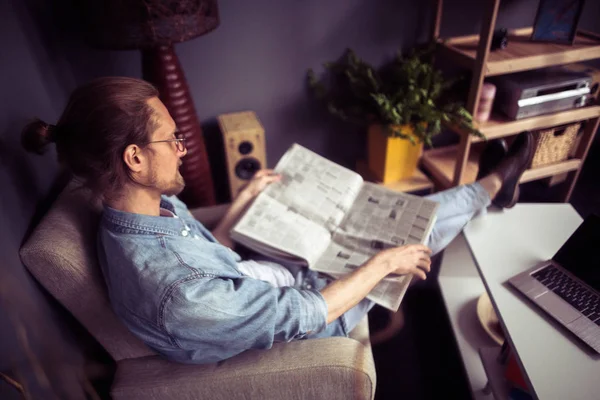 Freelancer sentado na cadeira colocando pernas na mesa de café . — Fotografia de Stock