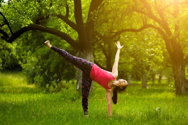 Jovem mulher de pé em meia lua pose, enquanto pratica ioga . — Fotografia de Stock