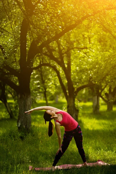Młodych kobiet Praktykuje jogę w rozszerzonej triangle pose. — Zdjęcie stockowe