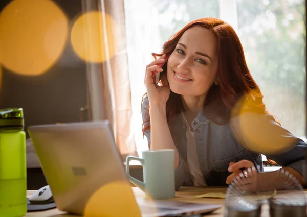 Schöne junge Freiberuflerin lächelt, während sie telefoniert. — Stockfoto