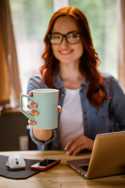 Vrouw die op freelance bedrijf mok in haar hand werkt. — Stockfoto