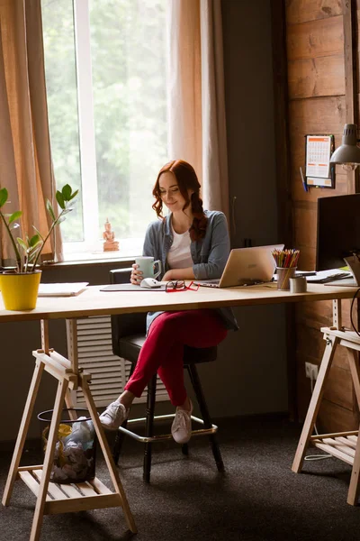 Vue générale du bureau à domicile moderne avec jeune pigiste aux cheveux roux . — Photo