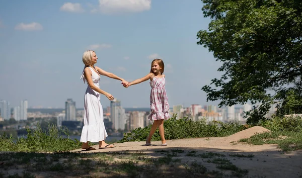 Madre e figlia che si tengono per mano, passeggiando nel parco cittadino . — Foto Stock