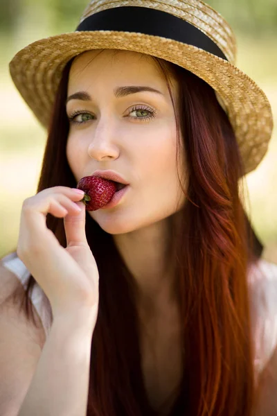 Donna sexy in cappello mangiare fragola in giardino . — Foto Stock