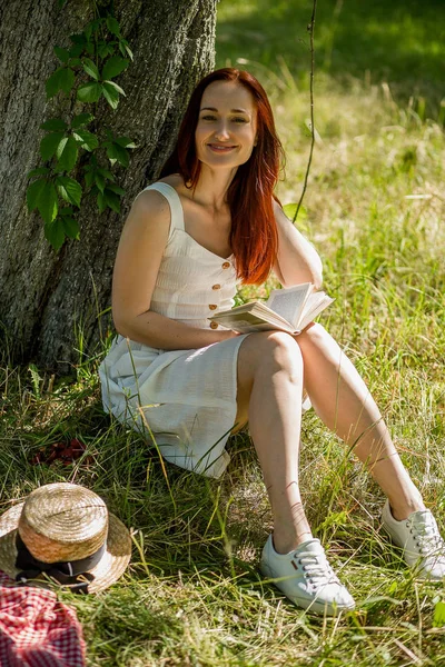 Romantica giovane donna in abito bianco seduta sull'erba in giardino . — Foto Stock