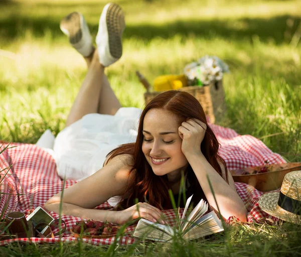 Κόκκινα μαλλιά γυναίκα ενθουσιασμένος με την ανάγνωση του βιβλίου στον κήπο. — Φωτογραφία Αρχείου
