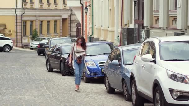 Travelgirl spaceru na ulicy, picia kawy i czytanie gazety. — Wideo stockowe