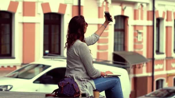 Jovem mulher turista bonita sentado no parapeito fazendo tiros selfie . — Vídeo de Stock