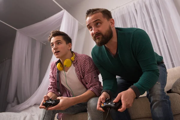 Concetto di videogioco, padre e figlio che si divertono a giocare insieme alla console . — Foto Stock