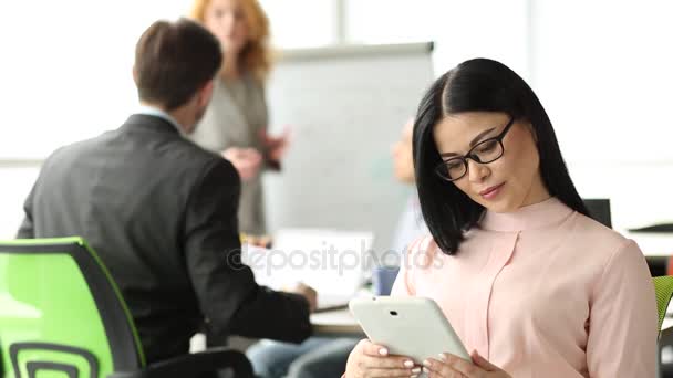 Praca zespołowa w biurze, brunetki kobieta pracę z cyfrowego tabletu na widok z przodu. — Wideo stockowe