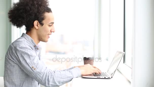 Vista lateral del joven que trabaja con el ordenador portátil, beber café . — Vídeo de stock